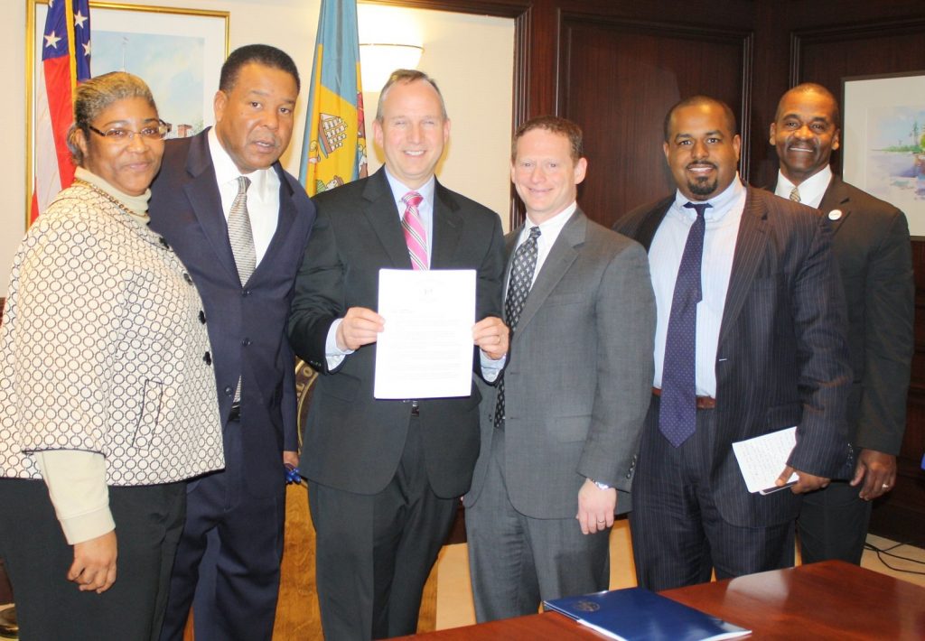 Governor Markell, flanked by five other individuals, holds up Executive Order 33, establishing the Delaware Council of Faith-Based Partnerships.